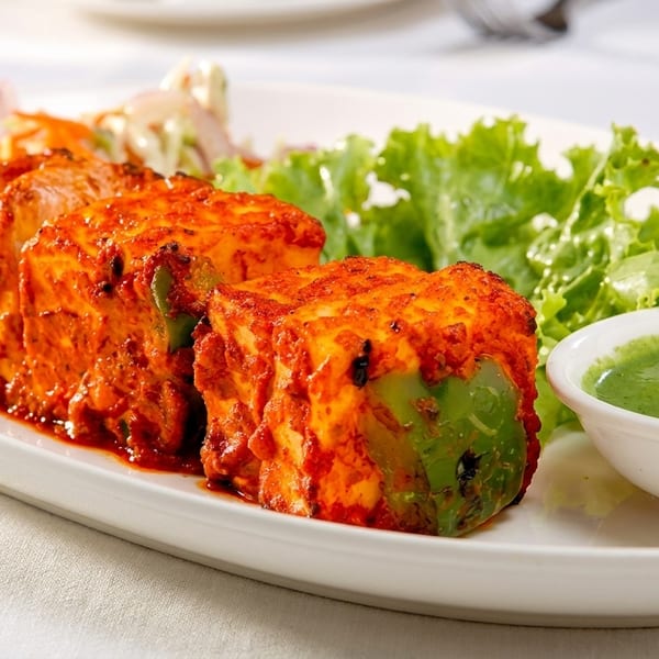 Spicy paneer tikka with green bell peppers, fresh lettuce, and a side of green chutney.